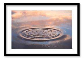 Water drop falling on water surface in evening  sunlight with reflection
