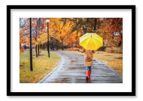 Woman with umbrella taking walk in autumn park on rainy day