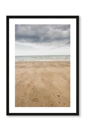Flat design is showing beach with pebbles and shells meeting calm sea under dark clouds