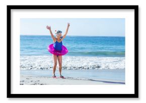 Senior woman raising arms, wearing snorkel mask, breathing snorkel, red fins and pink tube on beach