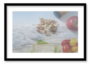 Resting nuts sitting on beach sand, featuring red apple green pear cherry tomatoes yellow sauce jar