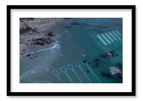 Hovering translucent blue circuit grid overlay over beach cove, with umbrellas, boulders and houses