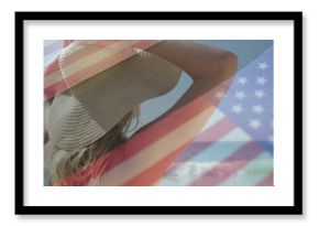 Gazing female beachgoer wearing straw sunhat and red bikini top at shoreline, with flag overlay