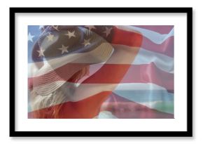 Raising bikini-clad female adjusting wide-brimmed sun hat on shore with ocean waves, flag overlay