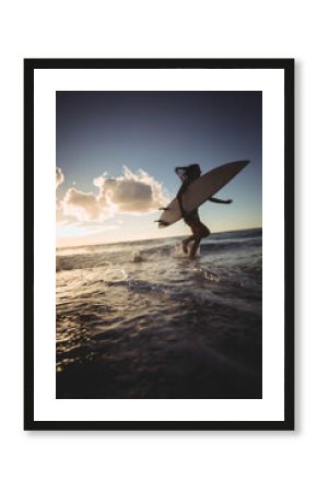 Long white surfboard leaning against gentle waves as warm sunset light sparkling on wet sand