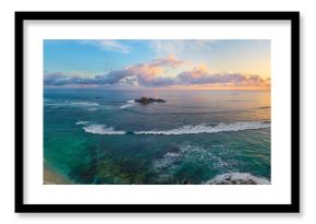 Panoramic view of tropical beach with surfers at sunset.