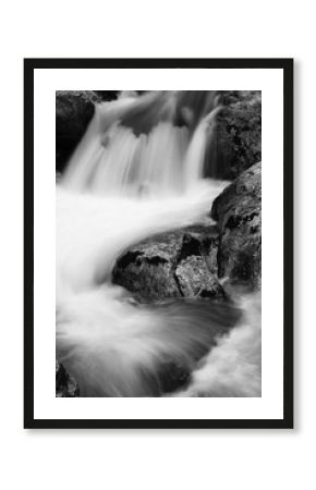 river rocks in smooth satin water flow of waterfall in black and white in long exposure