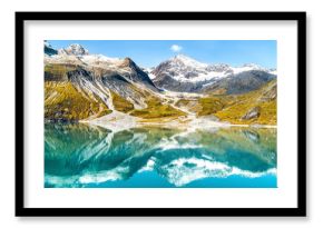 Glacier Bay National Park, Alaska, USA. Amazing glacial landscape showing mountain peaks and glaciers on clear blue sky summer day. Mirror reflection of mountains in still glacial waters.