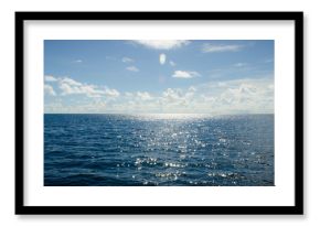 A panoramic scene of blue sky and the ocean with sunbeam shine above