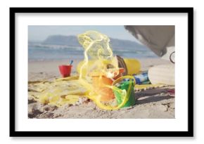 Arranging colorful sand buckets and shovel on sunny beach shore, with striped towel and cooler bag