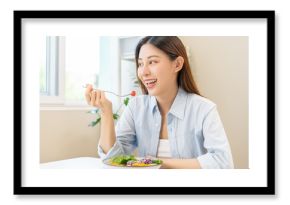 Diet concept, happy asian young woman hand use a fork to prick tomato, fresh vegetable or green salad, eat nutrition food  on table at home, low fat to good body. Girl getting weight loss for healthy.