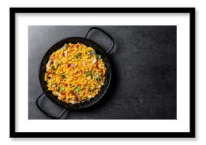 Yellow rice with chicken and vegetables on black slate background. Top view. Copy space