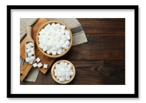 White sugar cubes in bowls and scoop on wooden table, flat lay. Space for text