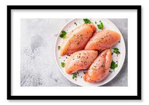 Raw chicken breasts seasoned with spices on a white plate.