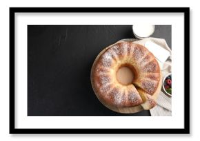 Freshly baked sponge cake, berries, milk and server on black table, top view. Space for text