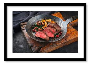 Barbecue dry aged beef steak - roast beef medium roasted, sliced with wild mushrooms, chestnuts, greens and cranberries in iron skillet pan