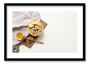 Bowl with tasty oatmeal, banana and nuts on white background