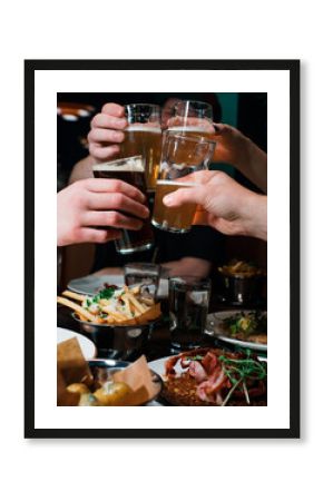 friends hands cheers beer together in a restaurant with food