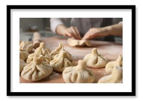 Woman making khinkali on table in kitchen, closeup