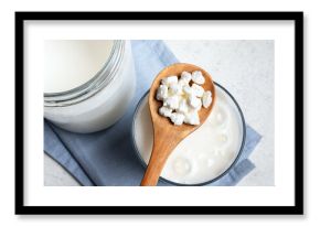 Milk kefir grains on wooden spoon and jar of kefir