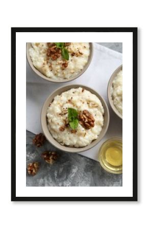 Delicious rice pudding with walnuts, mint and honey on grey table, flat lay