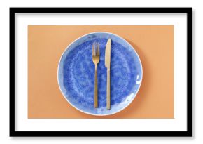 Empty plate and cutlery on light orange background, top view