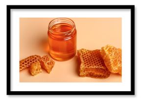 Jar with sweet honey and combs on orange background