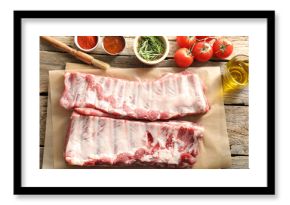 Raw pork ribs, spices and tomatoes on wooden table, flat lay