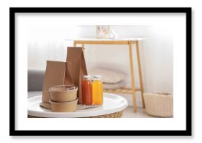 Paper bags with containers and juice on table in living room, closeup. Food delivery service