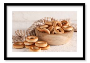Wooden bowl of tasty bagels on light background