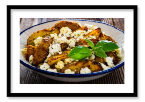 Greek style roasted potatoes with feta cheese on wooden table
