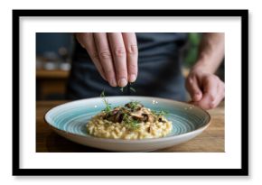 Close-up of hands sprinkling herbs over mushroom risotto