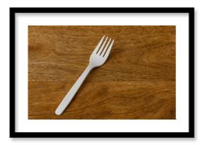 Disposable white plastic fork placed on a wooden table
