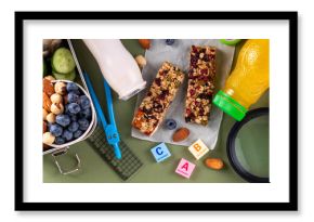 School healthy food for children. Preparing homemade balanced healthy lunch box for schooler, with sandwich, fruits, berries, juice, nuts. Ingredients and foods with school stationery and utensils