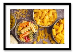 Bowls with different uncooked pasta on grey grunge background, closeup