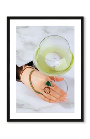 female hand with jewelry holding alcoholic fruit cocktail in hand