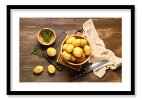 Bowl with raw baby potatoes and thyme on wooden background