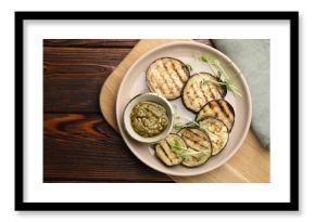 Grilled slices of eggplant with sauce and microgreens on wooden table, top view