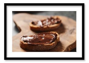 Ciabatta slices with chocolate spread on olive wood board