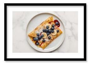 Banana and blueberry crepes served on a white surface, viewed from above