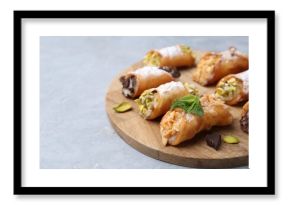 Delicious cannoli with cheese, nuts, powdered sugar, chocolate and mint on grey table, closeup. Space for text