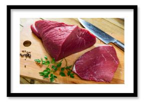 On cutting kitchen table there are fresh raw beef veal meat tenderloin. Raw beef tenderloin and spices, set of products for cooking baked and fried steak. Spices black pepper and herbs