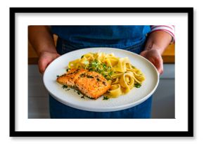 Woman holding plate with pasta with baked salmon steak, close-up
