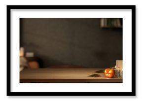 Glowing jack-o-lantern halloween pumpkin and candles aside books on wooden table in a dim lit room.