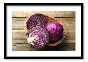 Whole and cut fresh red cabbages in wicker basket on wooden table, top view