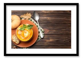 Tasty pumpkin cream soup with basil and croutons served in pumpkin on wooden table, flat lay. Space for text