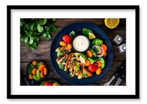 Grilled chicken breast, mayonnaise and vegetables on wooden table. Top view