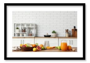 Tasty citrus fruits and jug of fresh juice on table in kitchen