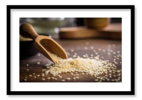 Roasted sesame seeds in scoop on wooden table.