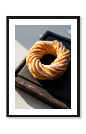 Circular Swirl Pastry with Icing Drizzle on a Dark Wooden Board in Sunlight